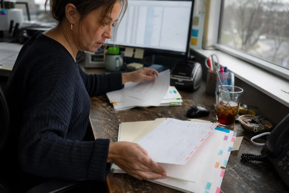 Agency account manager sorting printed keyword lists into colour-tabbed client folders
